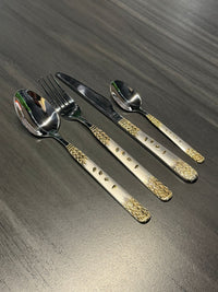 Premium stainless steel cutlery set with decorative gold-pattern handles including spoon, fork, knife, and teaspoon for catering and hospitality use.