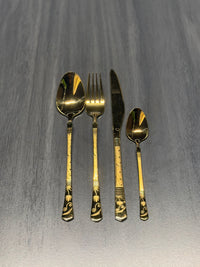 Luxury gold stainless steel cutlery set including spoon, fork, knife, and teaspoon with decorative engraved handles for catering and hospitality use.