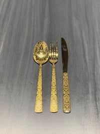 Luxury hammered gold stainless steel cutlery set with textured handles including fork, knife, and teaspoon for catering and hospitality use.