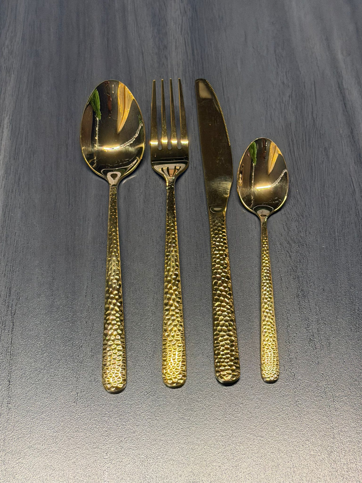 Luxury hammered gold stainless steel cutlery set with textured handles including dinner spoon, fork, knife, and teaspoon for catering and hospitality use.