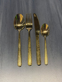 Luxury hammered gold stainless steel cutlery set with textured handles including dinner spoon, fork, knife, and teaspoon for catering and hospitality use.
